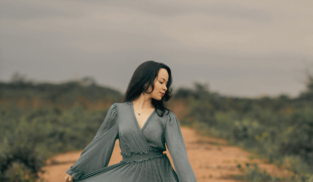 A girl in a dress walking on the fields.